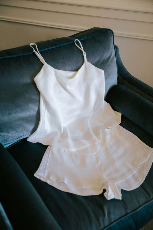 white top and shorts pyjama made with silk from orange peel laid over a blue teal velvet sofa